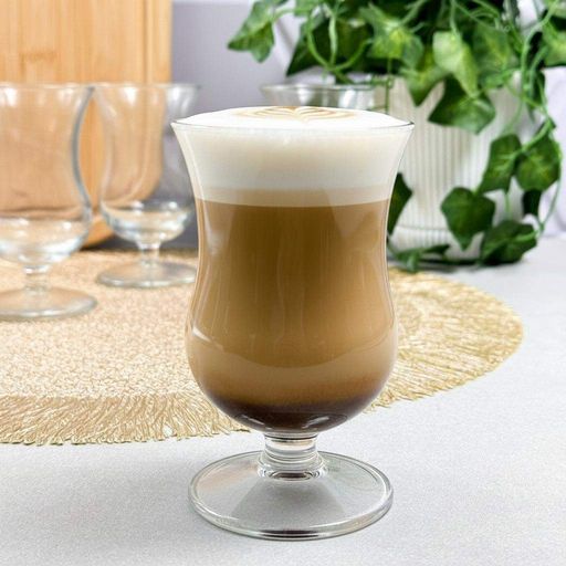Sklenený pohár na nôžke s latte a mliečnou penou